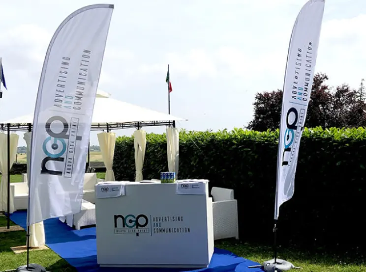 Allestimento evento all'aperto con bandiere e desk brandizzati Nuova Giga Print